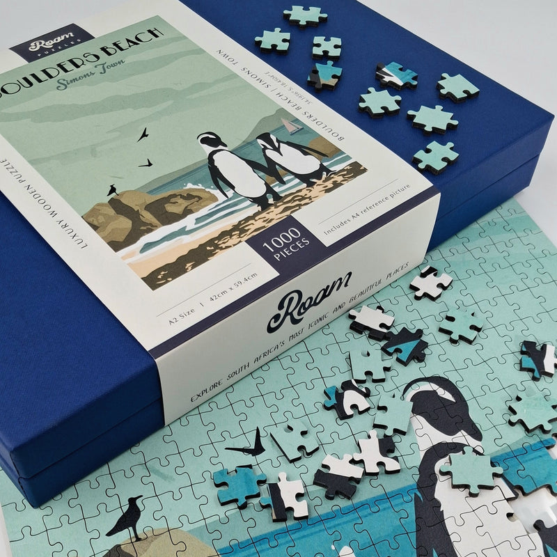Penguin-themed puzzle with pieces scattered on a surface, next to the packaging box.