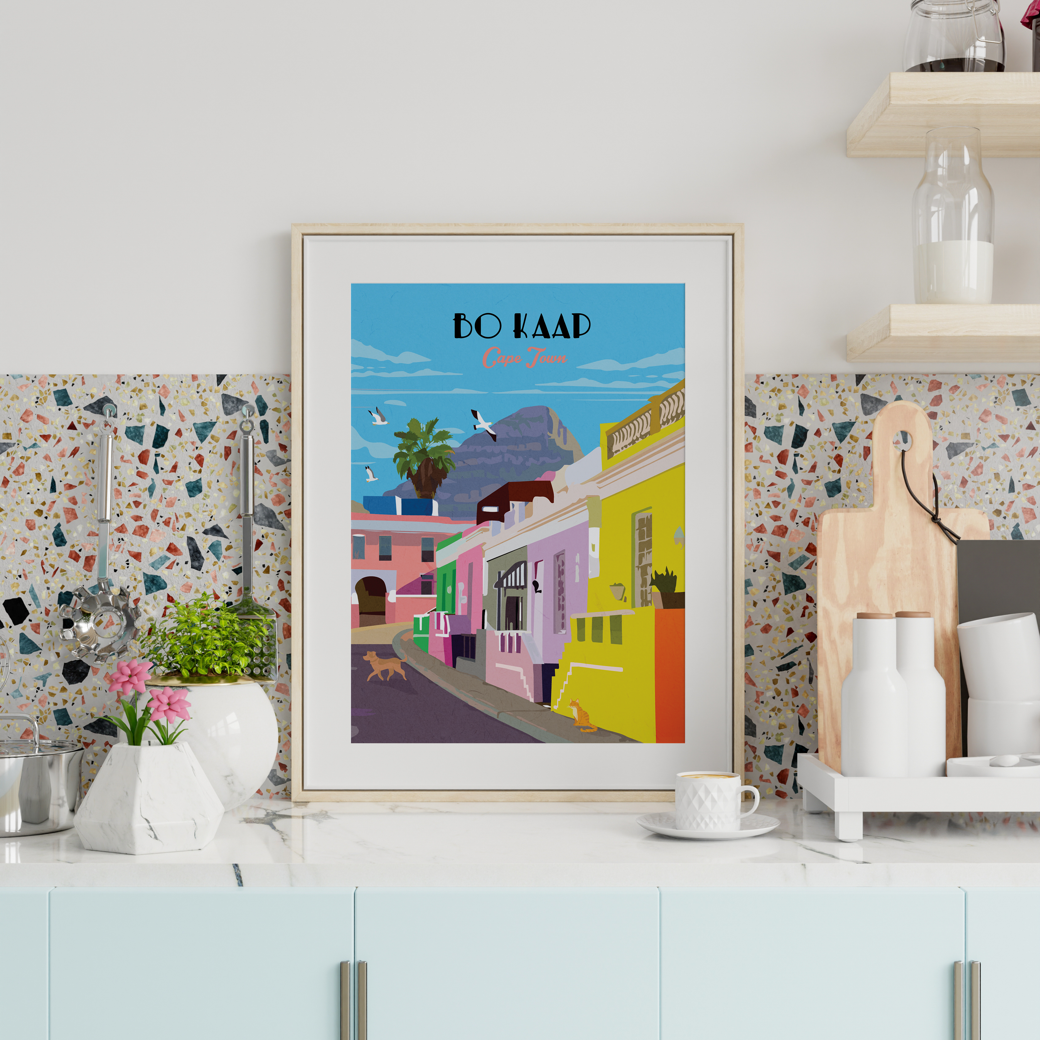 A framed travel poster of Bo Kaap, South Africa, styled on a kitchen countertop against a terrazzo backsplash. 