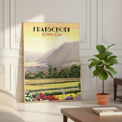 A framed vintage-style travel poster of Franschoek, Western Cape, leaning against a white paneled wall in a styled room next to a potted fiddle-leaf fig plant.
