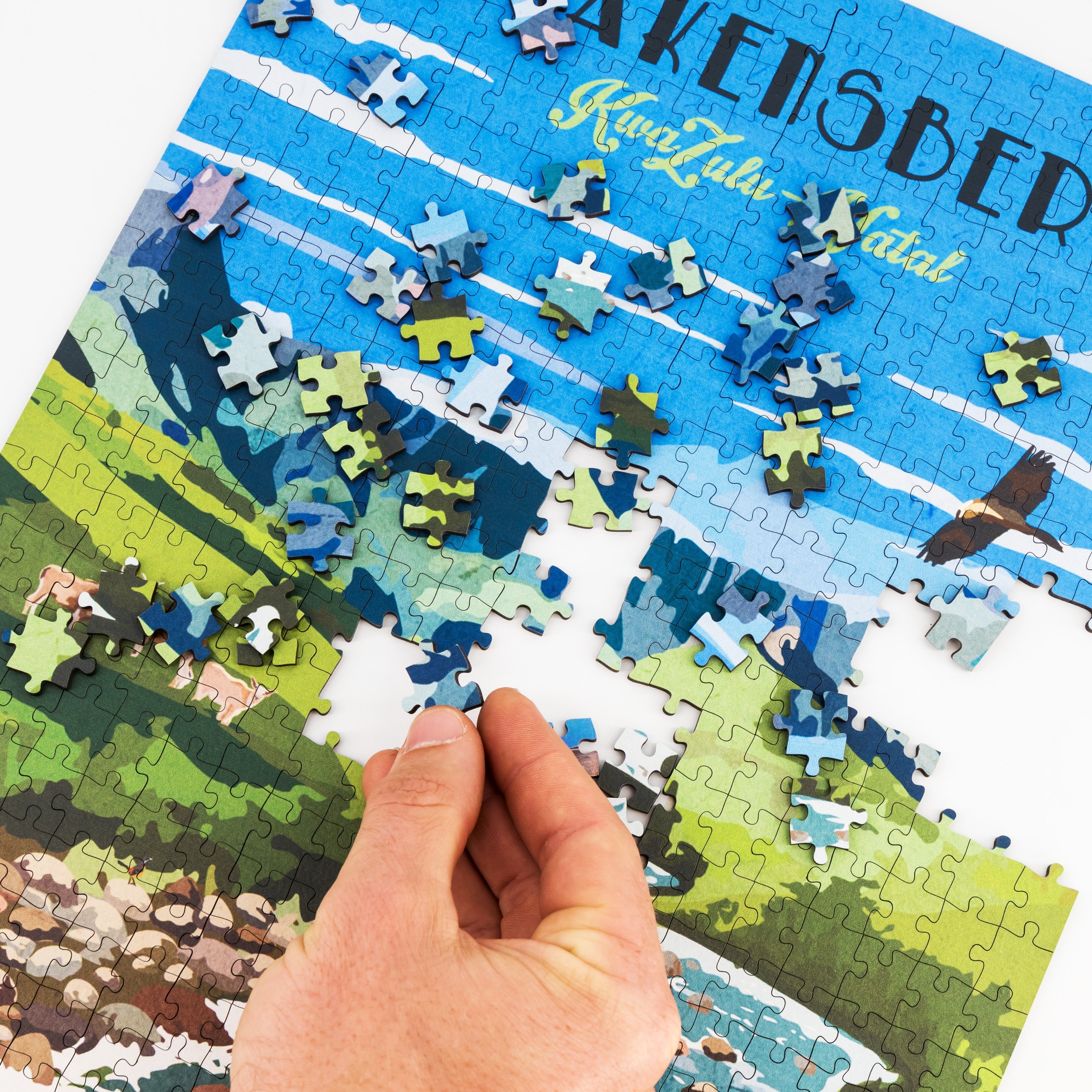 Jigsaw puzzle with a hand placing a piece, featuring a scenic design.