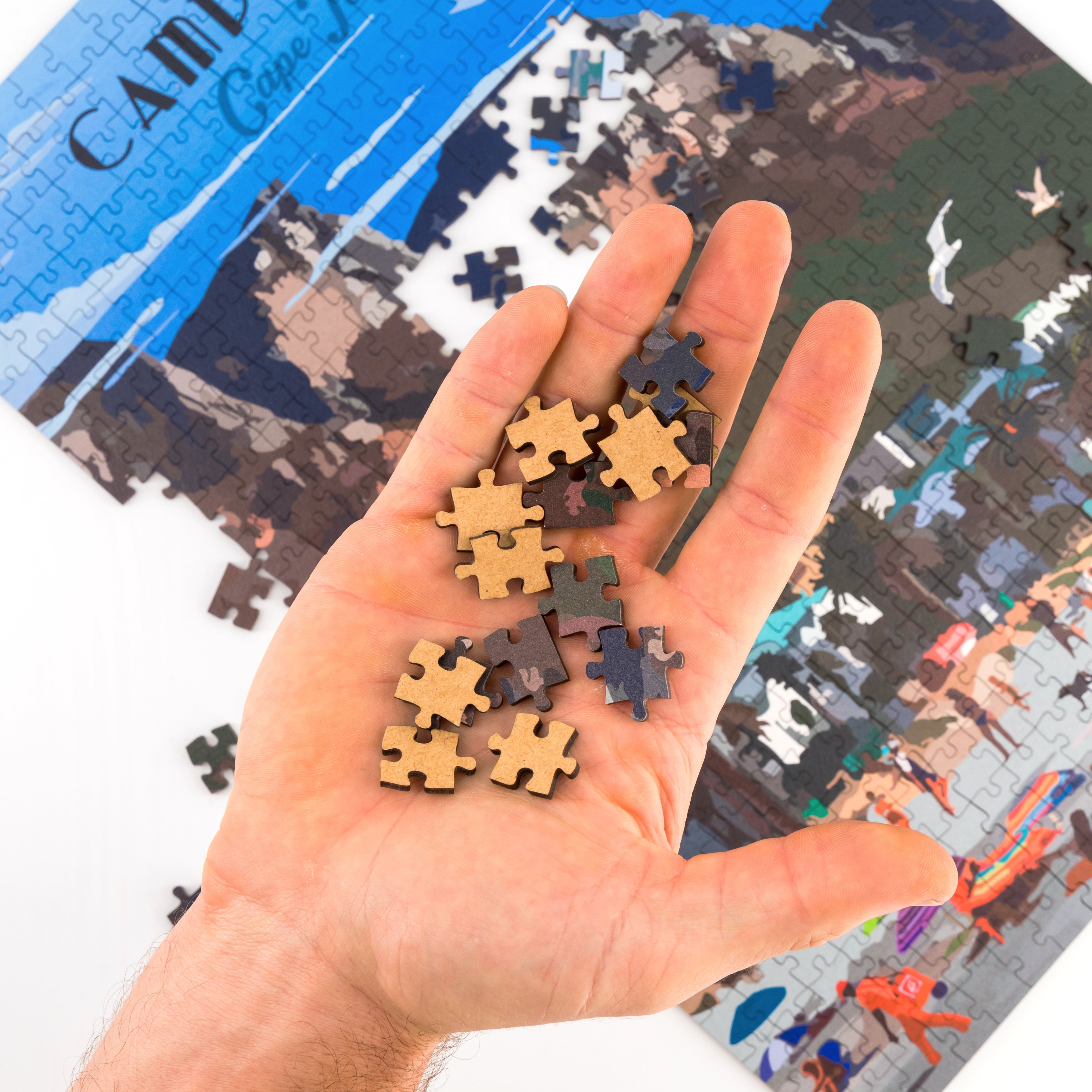 Hand holding puzzle pieces with a partially completed puzzle in the background