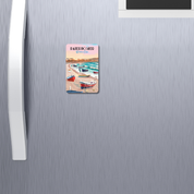 Fridge magnet with a beach scene design attached to a refrigerator.