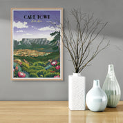 Framed poster of Cape Town on a wall with decorative vases on a table below.