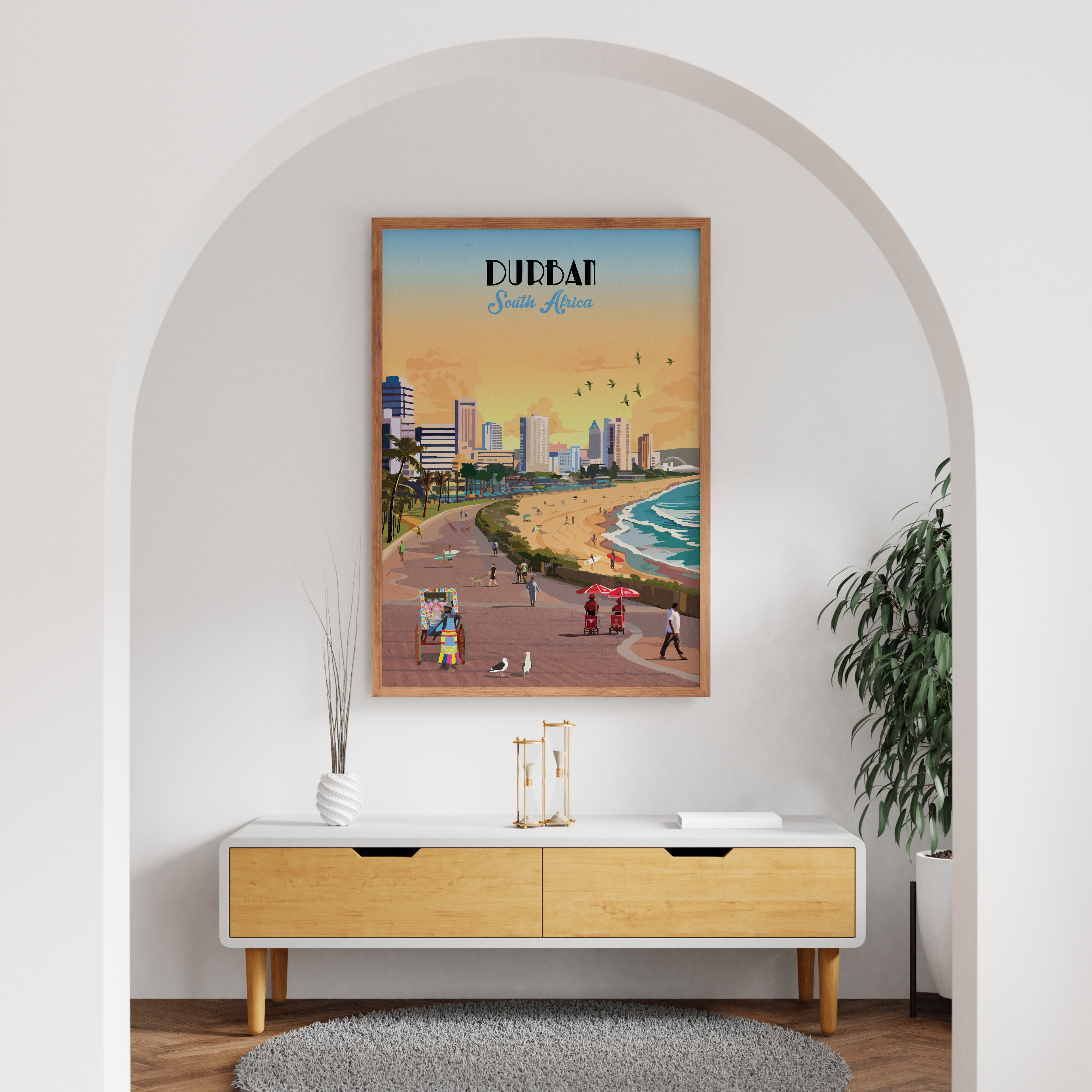 A framed travel poster of 'Durban, South Africa' featuring a retro beach boardwalk scene, displayed on a white wall in a modern room setting with an arched doorway, a wooden console table, and a potted plant.